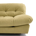 Close-up of a beige upholstered Milano sofa showing the tufted backrest, rounded armrest, and cushioned seat | Nue Modern