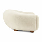 Side view of the curved Polar Bear Sofa in off-white sherpa showing its rounded back and short wooden legs | Nue Modern
