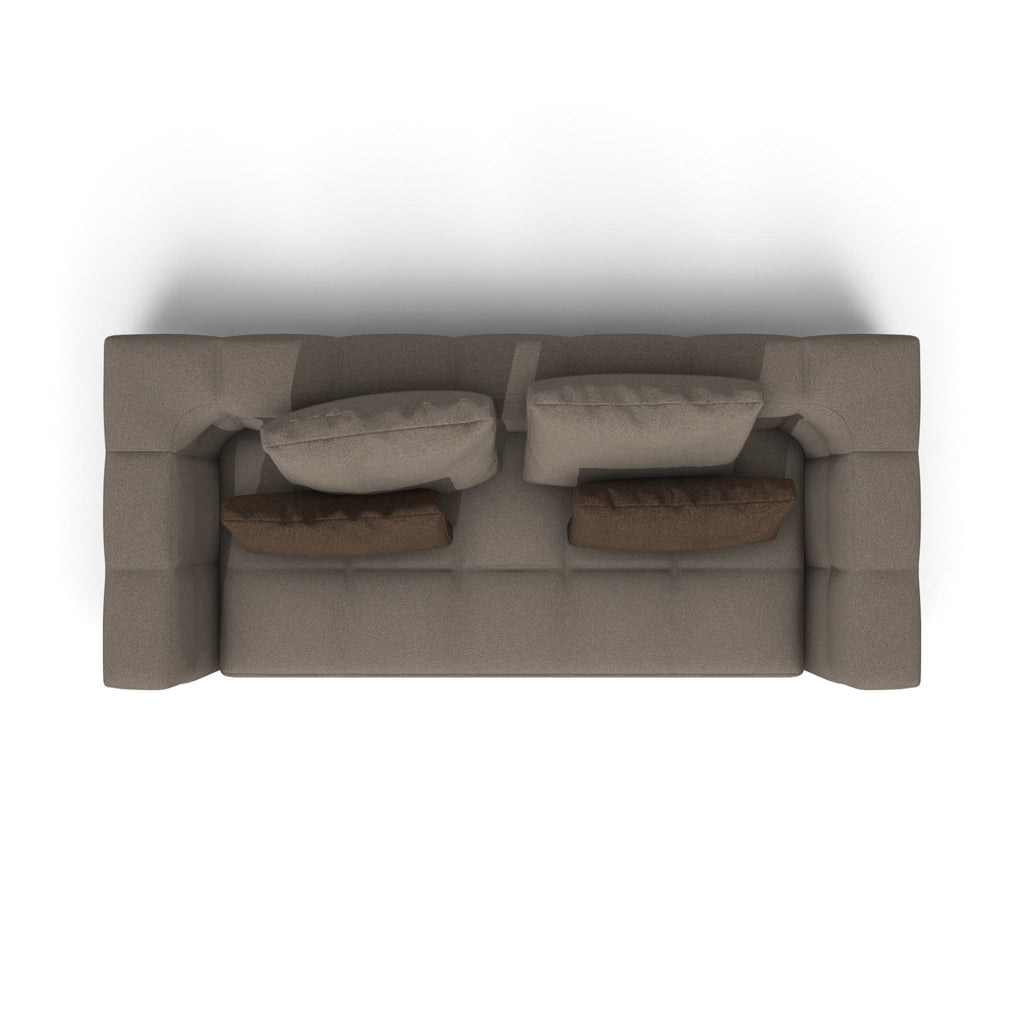 A top-down view of a modern, low-profile sofa in taupe fabric, styled with four matching cushions (two light taupe and two dark brown), set against a plain white background.