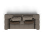 A top-down view of a modern, low-profile sofa in taupe fabric, styled with four matching cushions (two light taupe and two dark brown), set against a plain white background.