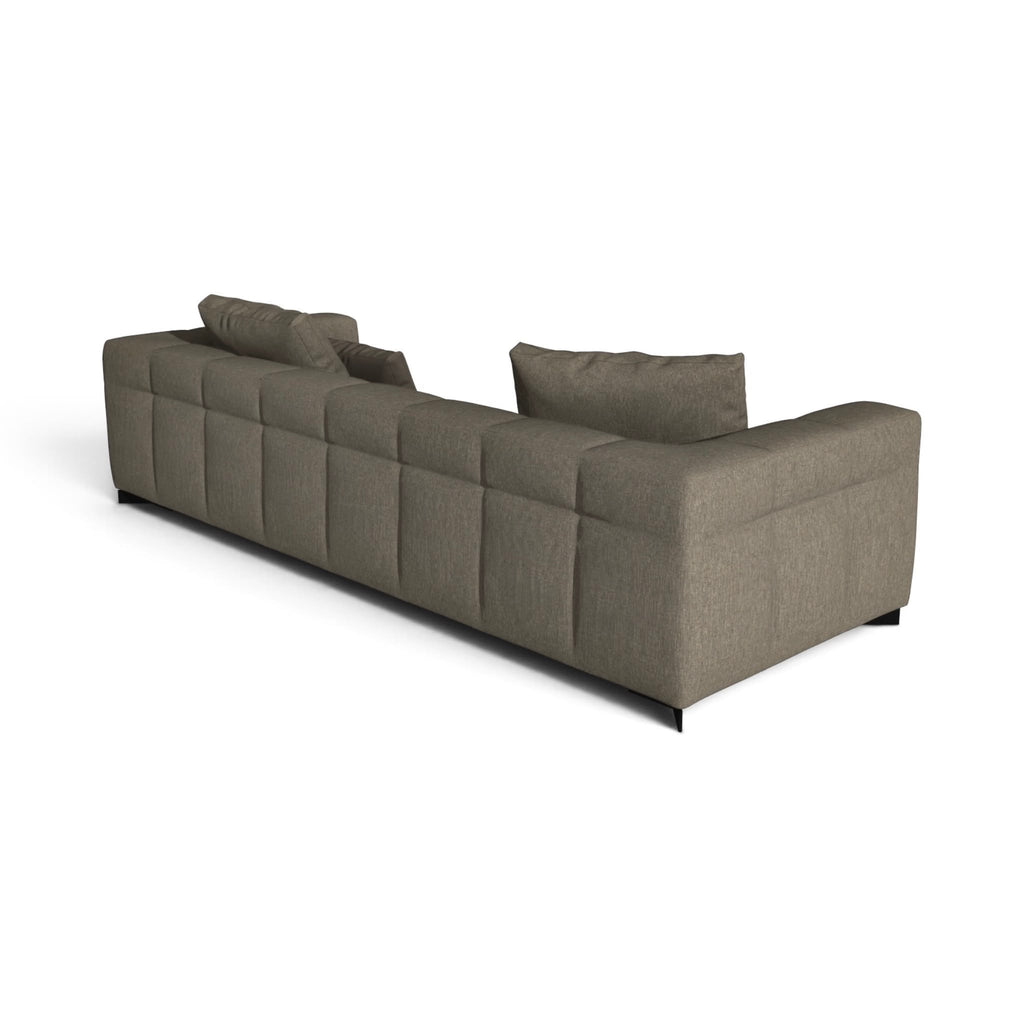 A modern sectional sofa in a textured taupe fabric, featuring a tufted grid pattern on the backrest and seat, with two matching throw pillows, shown from a three-quarters perspective on a white background.