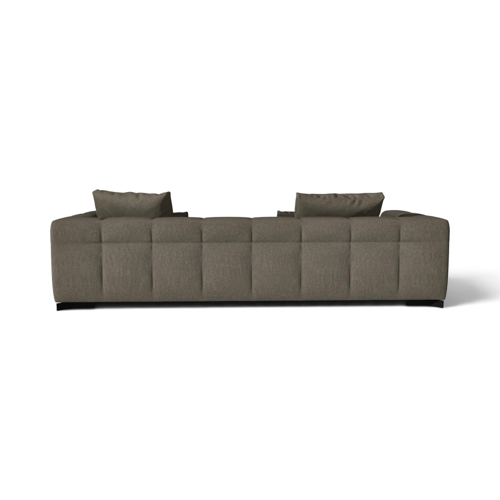 A modern low-profile sectional sofa upholstered in textured taupe fabric, featuring a tufted backrest and two matching throw pillows, shown from a straight-on perspective against a plain white background.