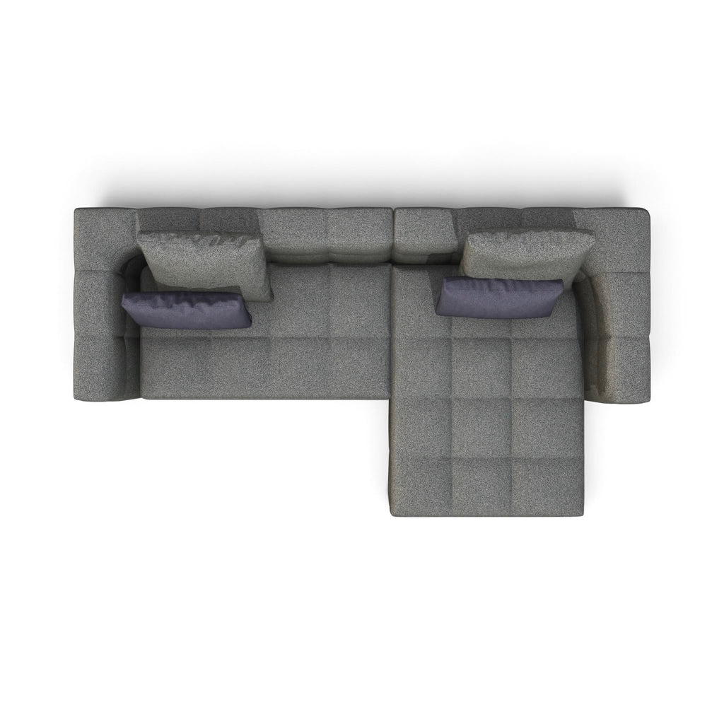 A top-down view of a modern gray sectional sofa with a chaise lounge and two dark purple accent pillows, isolated on a white background.
