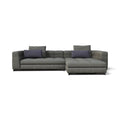 A modern gray fabric sectional sofa with a right-facing chaise lounge, featuring two dark purple accent pillows, shown against a plain white background.