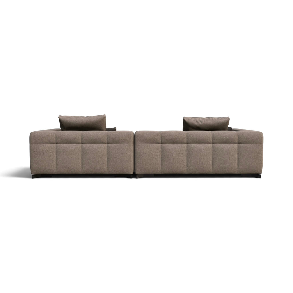 A modern modular sectional sofa upholstered in a textured taupe fabric, featuring deep channel tufting and two matching throw pillows, shown from a straight-on perspective against a plain white background.