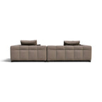 A modern modular sectional sofa upholstered in a textured taupe fabric, featuring deep channel tufting and two matching throw pillows, shown from a straight-on perspective against a plain white background.