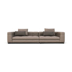 A modern two-seater sofa upholstered in a textured taupe-beige fabric, featuring two dark gray throw pillows and a low black base, shown against a plain white background.