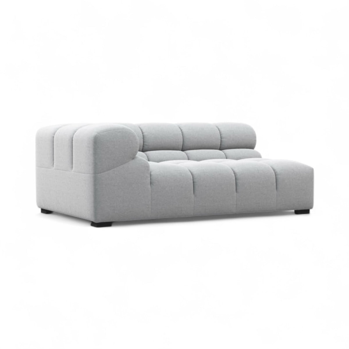 A modern light gray tufted chaise lounge sofa with a low, boxy silhouette and dark feet, shown against a plain white background.