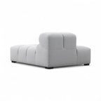 A light-grey upholstered Tufty TF018 sofa with a low, blocky design and dark feet, shown at a three-quarter angle